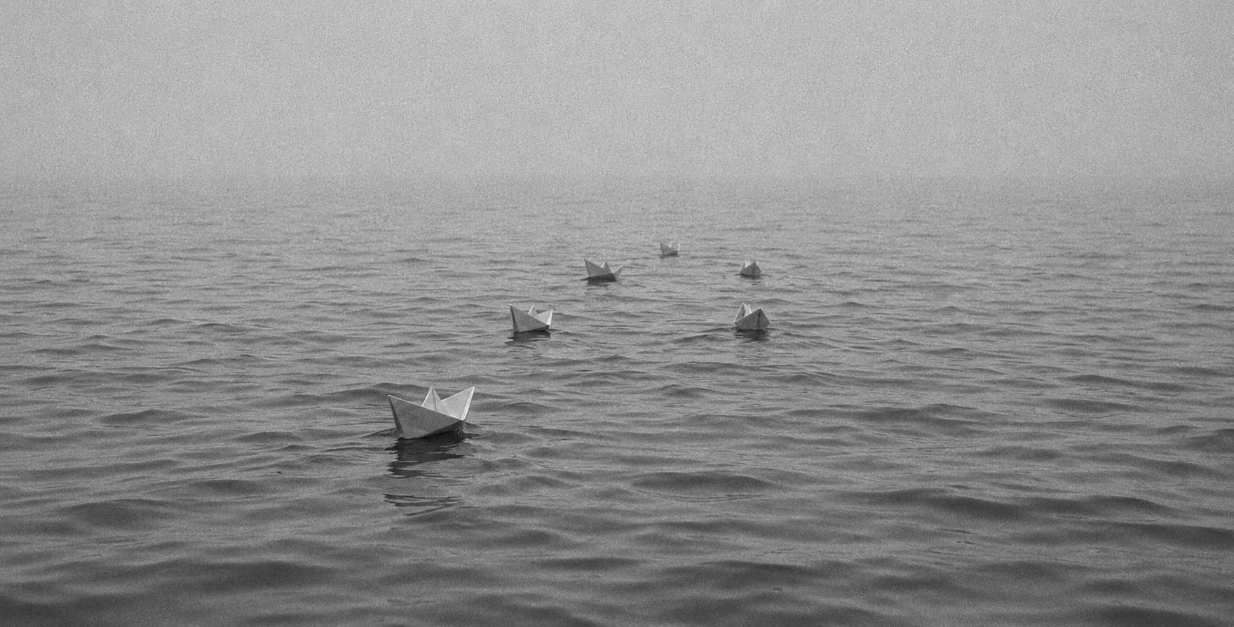 Paper boats on misty water, black and white